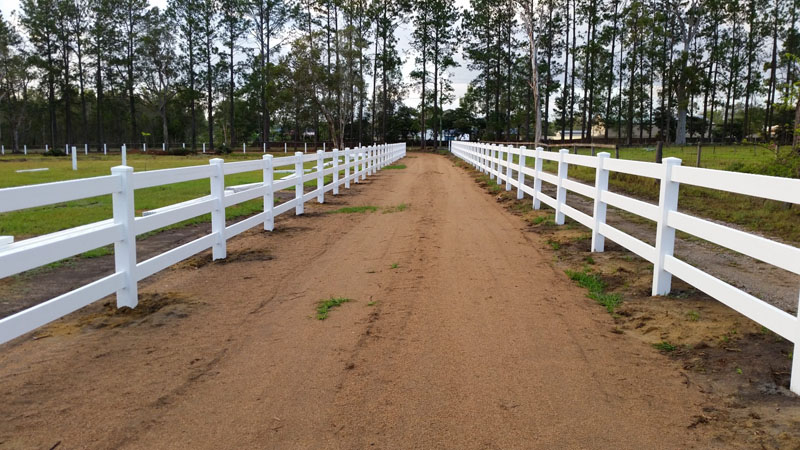 Newly built PVC post and rail fence on rural property.